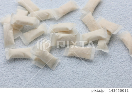Snus pouches arranged on a white surface showing the different shapes and sizes during a casual indoor scene 143450011