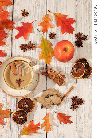 Indian masala chai with milk, ginger, anise, and cinnamon on an old wooden table with fallen autumn leaves. A traditional seasonal drink with spices, a cafe advertising card, a restaurant menu. Indian masala chai with milk, ginger, anise, and cinnamon on an old wooden table with fallen autumn leaves. A traditional seasonal drink with spices, a cafe advertising card, a restaurant menu. 143450491