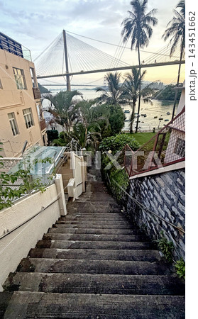 Steep concrete staircase leading down to a coastal view with a large cable-stayed suspension bridge Steep concrete staircase leading down to a coastal view with a large cable-stayed suspension bridge 143451662