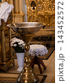Large silver baptismal font with brass stand inside cathedral church interior near altar 143452572