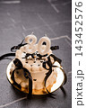 White frosting thirty birthday cake with black ribbons and candles on gold plate against dark grey slate background surface 143452576