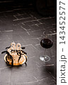 Elegant 30th birthday cake with white candles and black ribbon beside red wine glass on dark marble surface 143452577