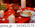 Intimate red table setting with textured glass, cake slice, candles, and fruit for romantic evening dining event. 143452579