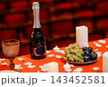 Champagne bottle with fruit platter and candles on red table in dark theater seats 143452581