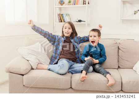 Happy children watching cartoon on tv at home, brother and sister having rest without parents, copy space 143453241