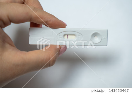 Woman fingers holding negative pregnancy test cassette horizontally for contraception control concept Woman fingers holding negative pregnancy test cassette horizontally for contraception control concept 143453467