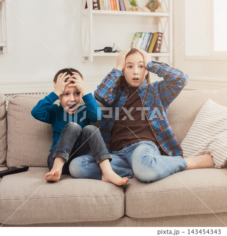 Frightened children watching scary movie at home, brother and sister having rest without parents, copy space 143454343