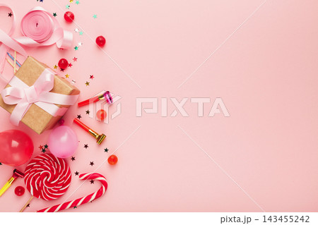Birthday party background, border of confetti, sweets, lollipops and gift on pink surface, copy space, top view 143455242