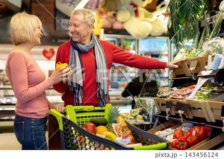 Smiling Elderly Caucasian Couple Enjoying Shopping Experience Together In Supermarket, Choosing Fresh Organic Produce And Having Fun, Engaging With Each Other While Pushing Cart. Smiling Elderly Caucasian Couple Enjoying Shopping Experience Together In Supermarket, Choosing Fresh Organic Produce And Having Fun, Engaging With Each Other While Pushing Cart. 143456124