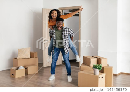 Smiling Black Couple Unpacking Boxes Together In Bright Apartment, Joyfully Celebrating Their New Home. Young Adults Filled With Excitement And Happiness In Modern Living Space. Home Concept. Smiling Black Couple Unpacking Boxes Together In Bright Apartment, Joyfully Celebrating Their New Home. Young Adults Filled With Excitement And Happiness In Modern Living Space. Home Concept. 143456570
