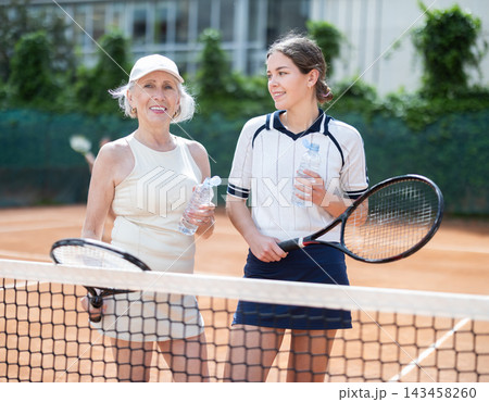 Elderly and young woman chatting on tennis court 143458260