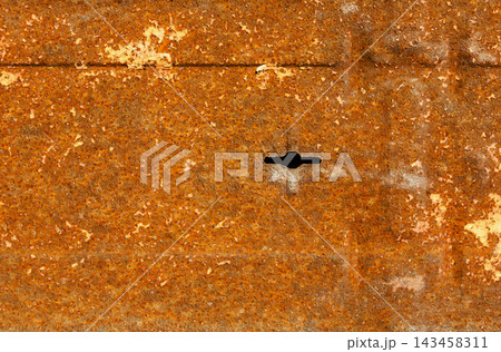 A rusty metal surface with a noticeable hole. The texture and color imply exposure to weather and time in an industrial area. The background highlights the decay process. 143458311