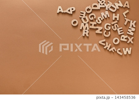 Scattered wooden letters lay on a brown surface. The letters are randomly placed, creating a simple scene. This setup is ideal for educational activities and crafting ideas. Scattered wooden letters lay on a brown surface. The letters are randomly placed, creating a simple scene. This setup is ideal for educational activities and crafting ideas. 143458536