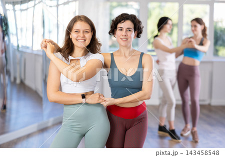 Two enthusiastic young women dancing salsa as dance partners in studio Two enthusiastic young women dancing salsa as dance partners in studio 143458548