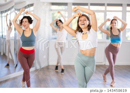 Women in casual clothes studying modern dance element in classroom Women in casual clothes studying modern dance element in classroom 143458619