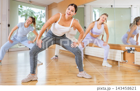 Women in casual clothes studying modern dance element in classroom Women in casual clothes studying modern dance element in classroom 143458621