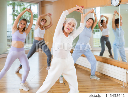Women learning modern dance movements at class together Women learning modern dance movements at class together 143458641