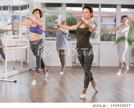 Graceful women of different ages practice various ballet movements in choreographic studio 143458657