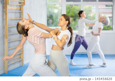 Woman and girl in gym perform basic elements of krav maga self-defense system. Woman and girl in gym perform basic elements of krav maga self-defense system. 143458820