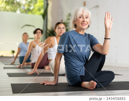Portrait of women practicing Matsyendrasana known as Lord of Fishes Pose during group yoga training 143458881