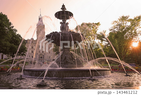 Quebec City Parliament illuminated in the evening by sun rays between trees with The Fontaine de Tourny on the foreground, Canada Quebec City Parliament illuminated in the evening by sun rays between trees with The Fontaine de Tourny on the foreground, Canada 143461212