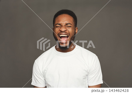 A set of images shows a young man with a big smile and laughter. He is expressing strong emotions. The background is plain, focusing attention on the collection of joyous moments. 143462428