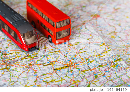 A toy train and a toy bus are placed on a map of Germany. The map shows various cities and routes. The scene captures a moment of exploration and travel planning. 143464159