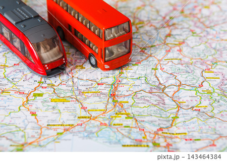 Two scale models of a bus and a train rest on a detailed map. The map displays roads and locations in a city and its surroundings. This setup suggests planning for travel. 143464384