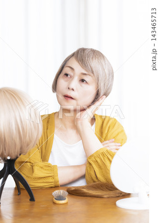 薄毛に悩みウイッグをつけるシニア女性 薄毛に悩みウイッグをつけるシニア女性 143465713