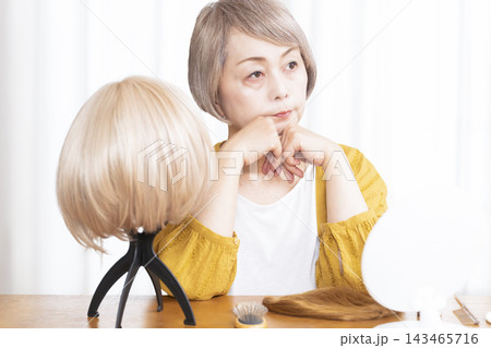 薄毛に悩みウイッグをつけるシニア女性 薄毛に悩みウイッグをつけるシニア女性 143465716