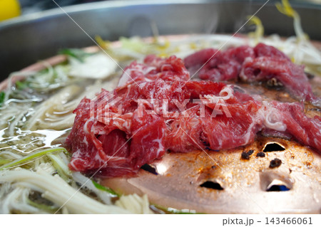 Raw marinated beef Bulgogi with enoki mushrooms, green onions and bok choy on a traditional copper grill pan Raw marinated beef Bulgogi with enoki mushrooms, green onions and bok choy on a traditional copper grill pan 143466061