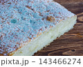 A slice of bread heavily covered in blue-green and white mold on a wooden table 143466274