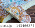 Two pieces of moldy bread stacked on a wooden table 143466275