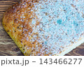 A piece of focaccia bread partially covered in mold on a wooden table. 143466277