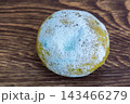 A whole lemon covered in white and blue mold on a wooden surface 143466279