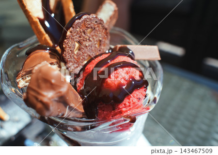 Close-up of a delicious ice cream sundae decorated with chocolate syrup and wafers Close-up of a delicious ice cream sundae decorated with chocolate syrup and wafers 143467509