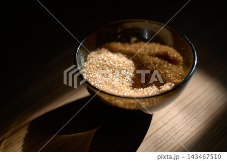 Close-up of brown cane sugar in small glass bowl on wooden table 143467510