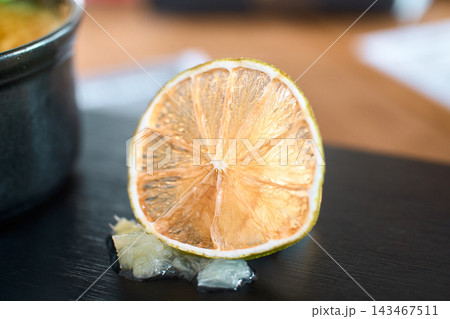 Close-up view of a dried lime slice resting on a dark surface 143467511
