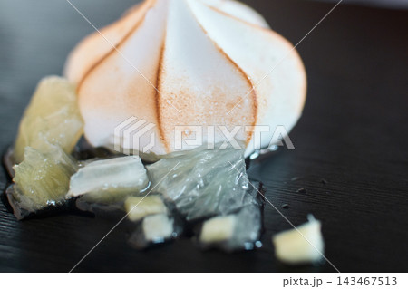 Close-up of a toasted meringue dessert served with citrus fruit pieces on a plate 143467513