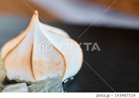 Close-up of a sweet toasted meringue on a dark surface in a kitchen Close-up of a sweet toasted meringue on a dark surface in a kitchen 143467514