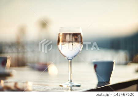 A close-up view of a glass of wine sitting on a wooden table outdoors A close-up view of a glass of wine sitting on a wooden table outdoors 143467520