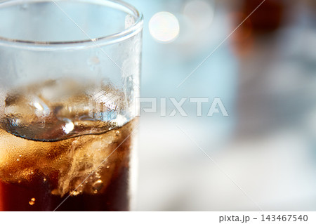 Close-up of a refreshing glass of cold cola with ice cubes and condensation drops Close-up of a refreshing glass of cold cola with ice cubes and condensation drops 143467540