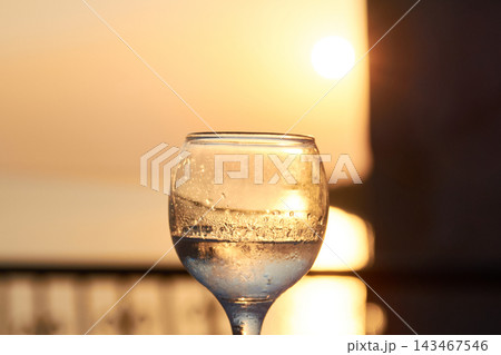 Close-up of a chilled glass of traditional Greek ouzo during a scenic sunset 143467546