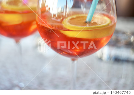 Close-up of refreshing orange spritz cocktails garnished with citrus slices and a straw Close-up of refreshing orange spritz cocktails garnished with citrus slices and a straw 143467740