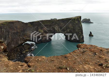 Volcanic rock arch at Dyrholaey peninsula over the ocean, Iceland 143469427