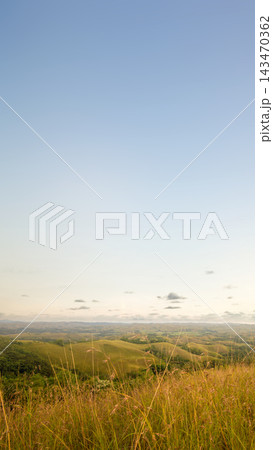 A panoramic scenic view of rolling green hills, valleys, and distant horizons under a bright sky with soft clouds, shot from a grassy hilltop. Nature, natural or quotes background 143470362