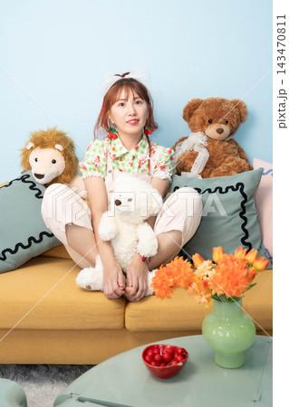 ぬいぐるみとソファーに座る若い女性 ぬいぐるみとソファーに座る若い女性 143470811