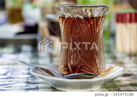 Black tea herbal Turkish glass mug armud stands on table coffee shop restaurant Black tea herbal Turkish glass mug armud stands on table coffee shop restaurant 143473196