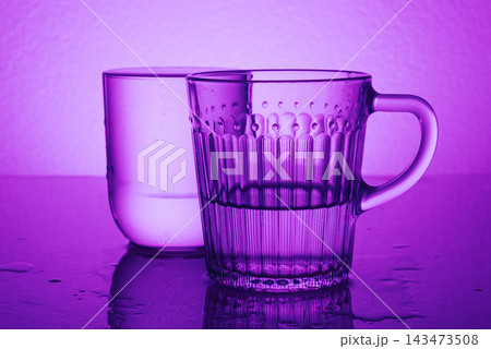 Glass clear transparent Mugs In Purple Neon Light Low Key abstract Still Life Glass clear transparent Mugs In Purple Neon Light Low Key abstract Still Life 143473508