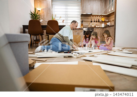 Family bonding while crafting together in a cozy living space 143474011
